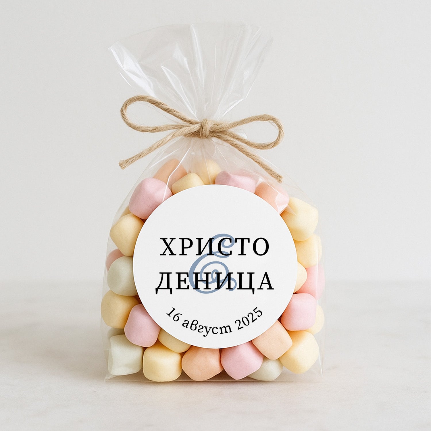 Персонализиран сватбен стикер с изчистен шрифт, поставен върху опаковка с маршмелоу – подходящ за декорация на сладки изненади за гости.
