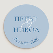 Детайлен изглед на кръгъл стикер със светлосин фон, тъмен текст и елегантен бял амперсанд – модерен дизайн за сватбени етикети.

